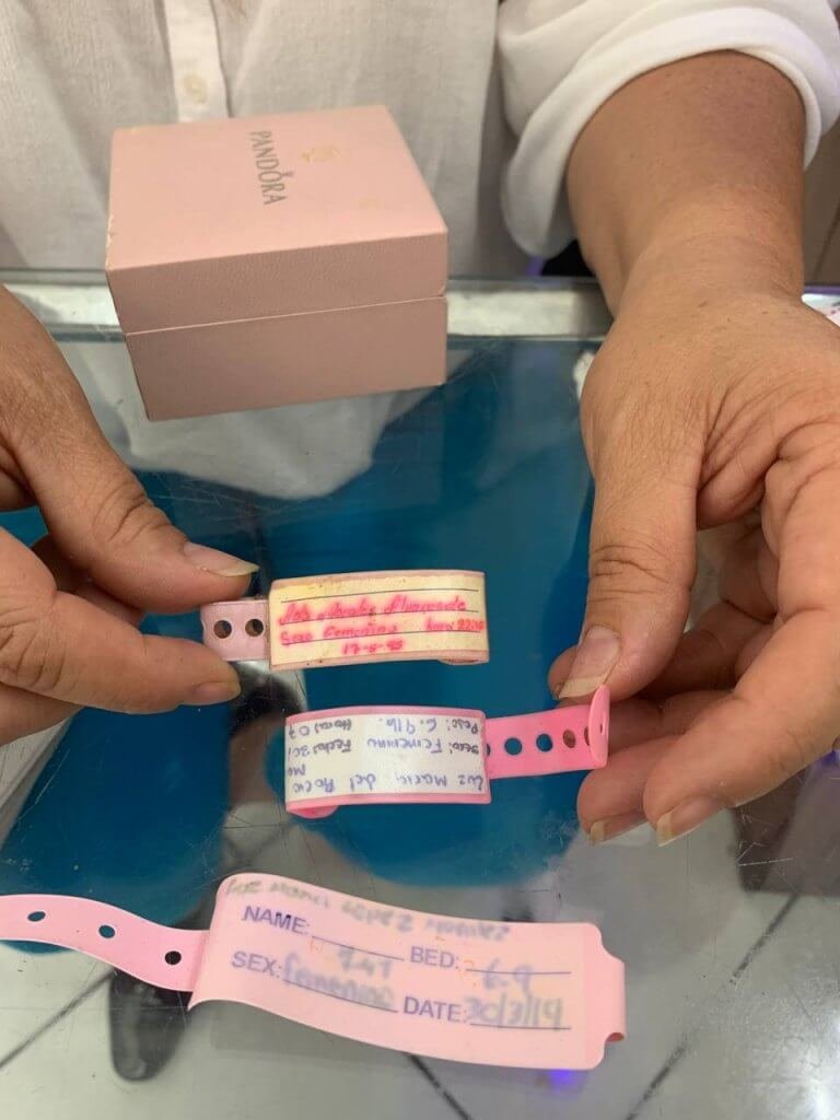  Ada enseña dos brazaletes de nacimiento: el suyo y el de Luz María, y el de Luz María cuando estuvo embarazada. Foto: Andrea Rodríguez. 