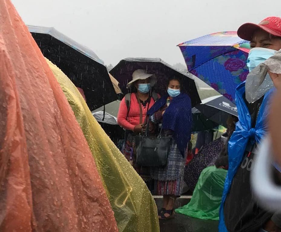  Mujeres y pobladores se resguardan de la lluvia con sombrillas y nylons en Totonicapán.Foto: Paolina Albani. 