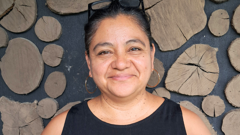 Retrato de Gisela. Una mujer morena con anteojos sobre la cabeza y camisa negra sin mangas.