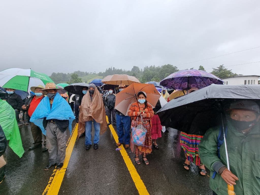  La lluvia empezó a caer después de la hora del almuerzo. La gente se quedó para escuchar a las autoridades indígenas y se cubrió con sombrillas y nylons. Foto: Paolina Albani. 