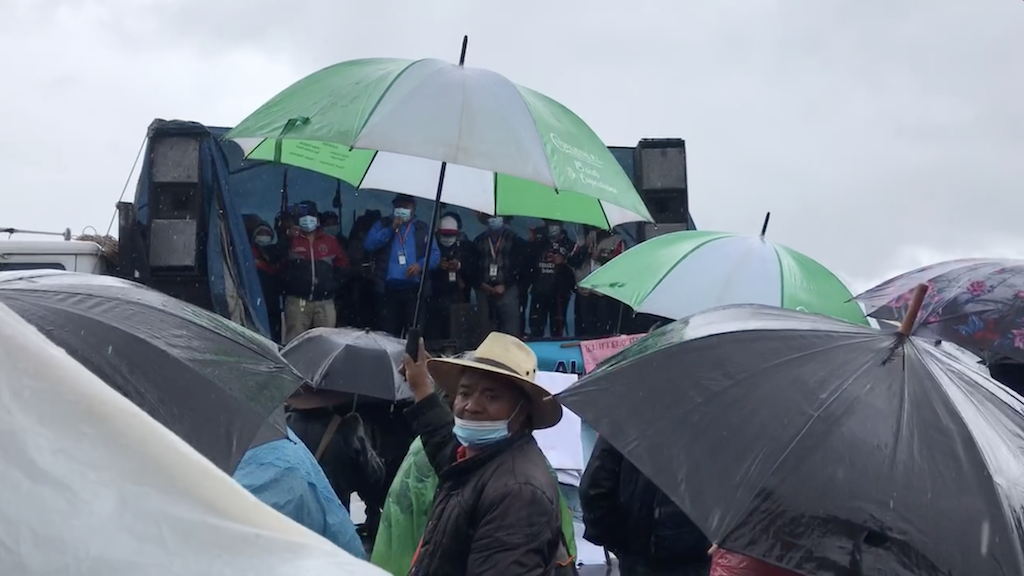  Hombre se voltea a buscar a su familia cuando la lluvia empieza a caer. Atrás, las autoridades indígenas imparten mensajes de lucha.Foto: Paolina Albani. 
